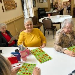People sitting at a table, playing bingo in a community room.